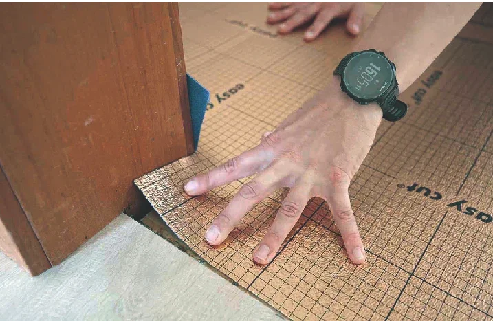 Hand legt eine Trittschall-Unterlagsmatte am Türrahmen aus